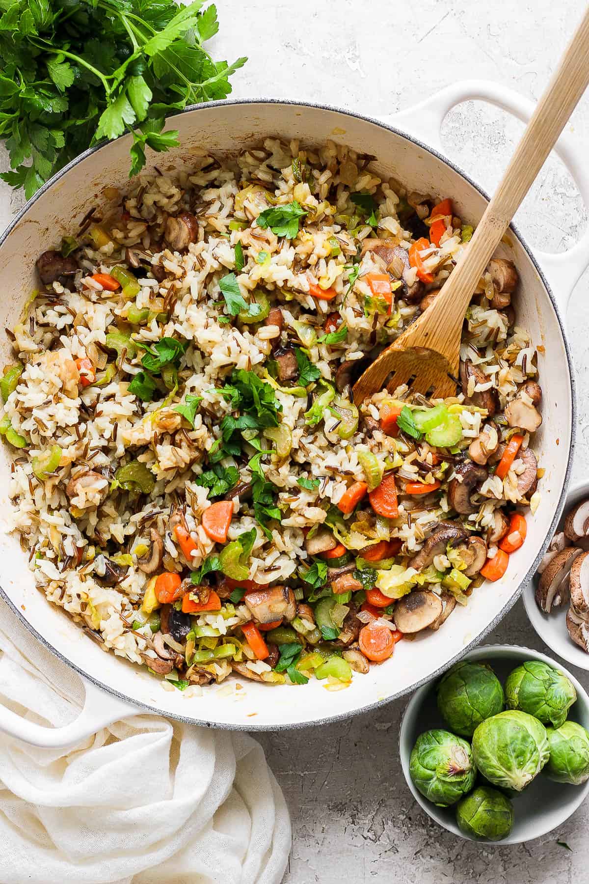 A fully cooked wild rice pilaf in the skillet with a wooden spoon.