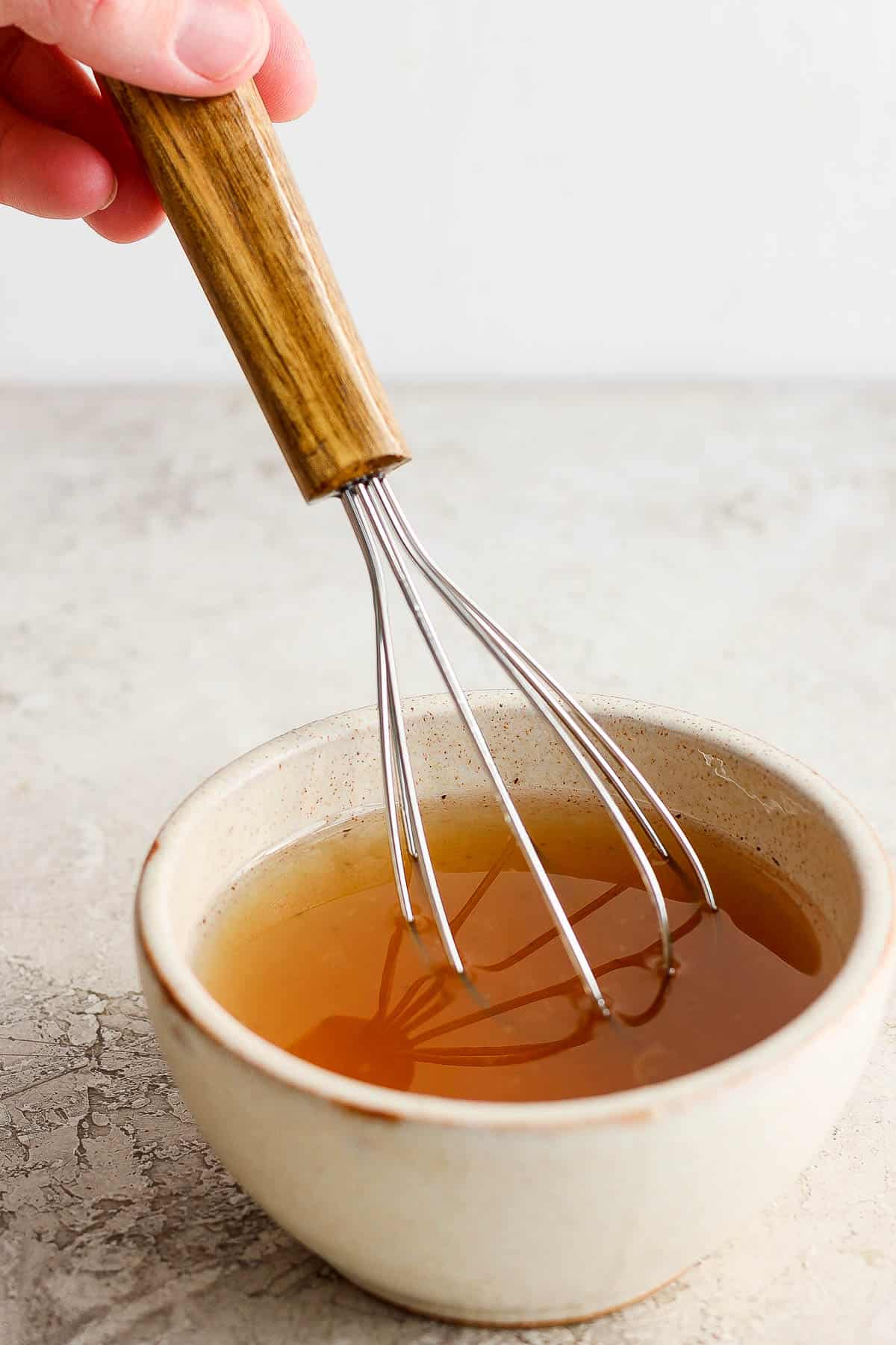 The dressing being whisked in a small bowl.