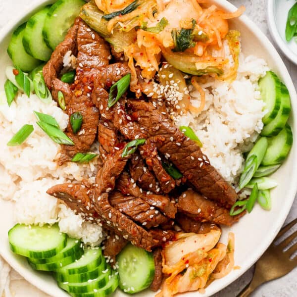Top down shot of a beef bulgogi bowl with kimchi, rice and cucumbers.