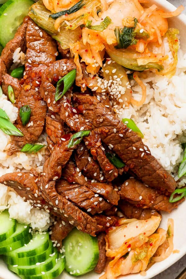 Top down shot of a beef bulgogi bowl with kimchi, rice and cucumbers.