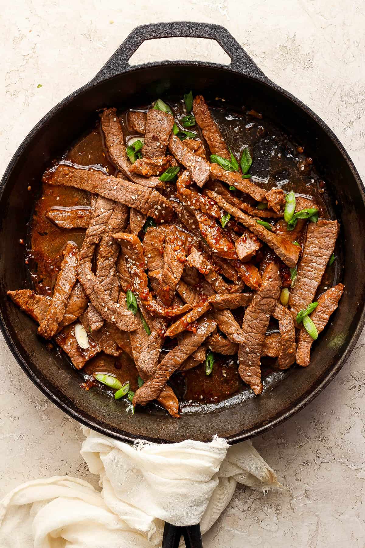 Beef bulgogi in a skillet topped with green onions.