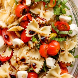 Close up top shot of a caprese pasta salad with bow tie pasta, tomato, mozzarella and basil.