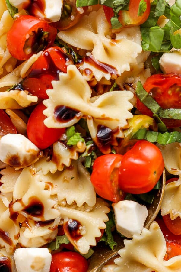 Close up top shot of a caprese pasta salad with bow tie pasta, tomato, mozzarella and basil.