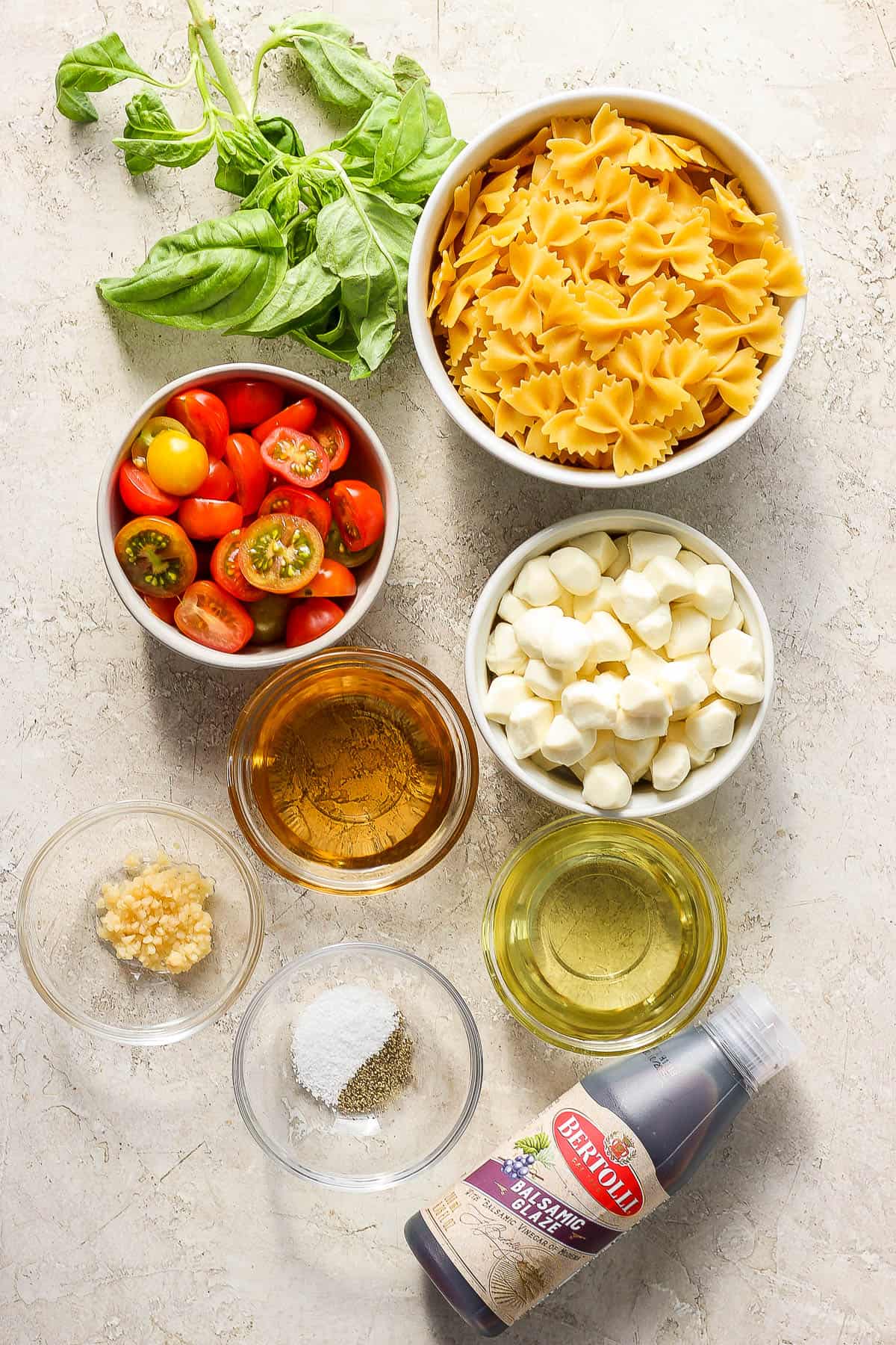 Caprese pasta salad ingredients in separate bowls.