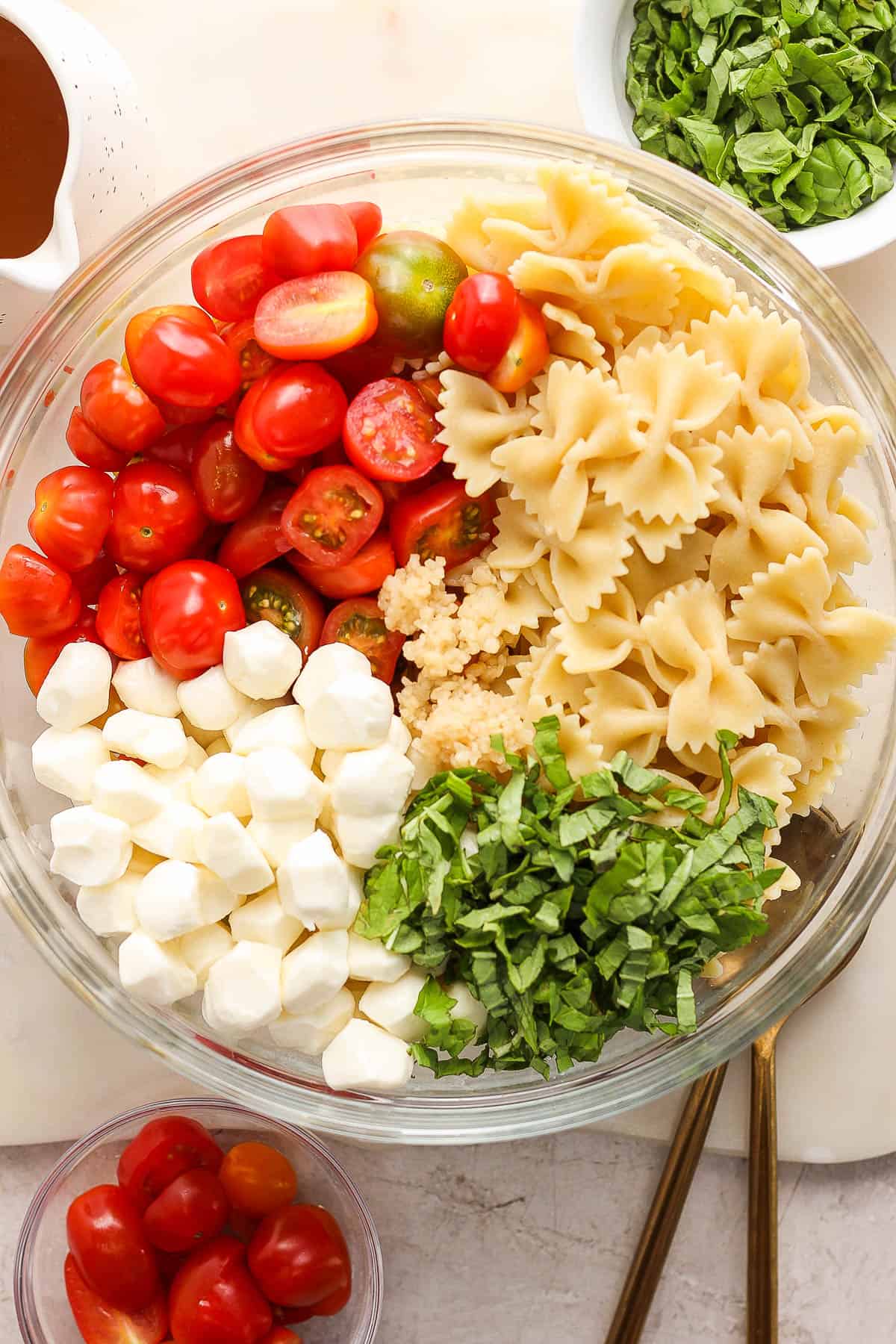 A large glass bowl with the pasta, tomatoes, basil, and mozzarella cheese.
