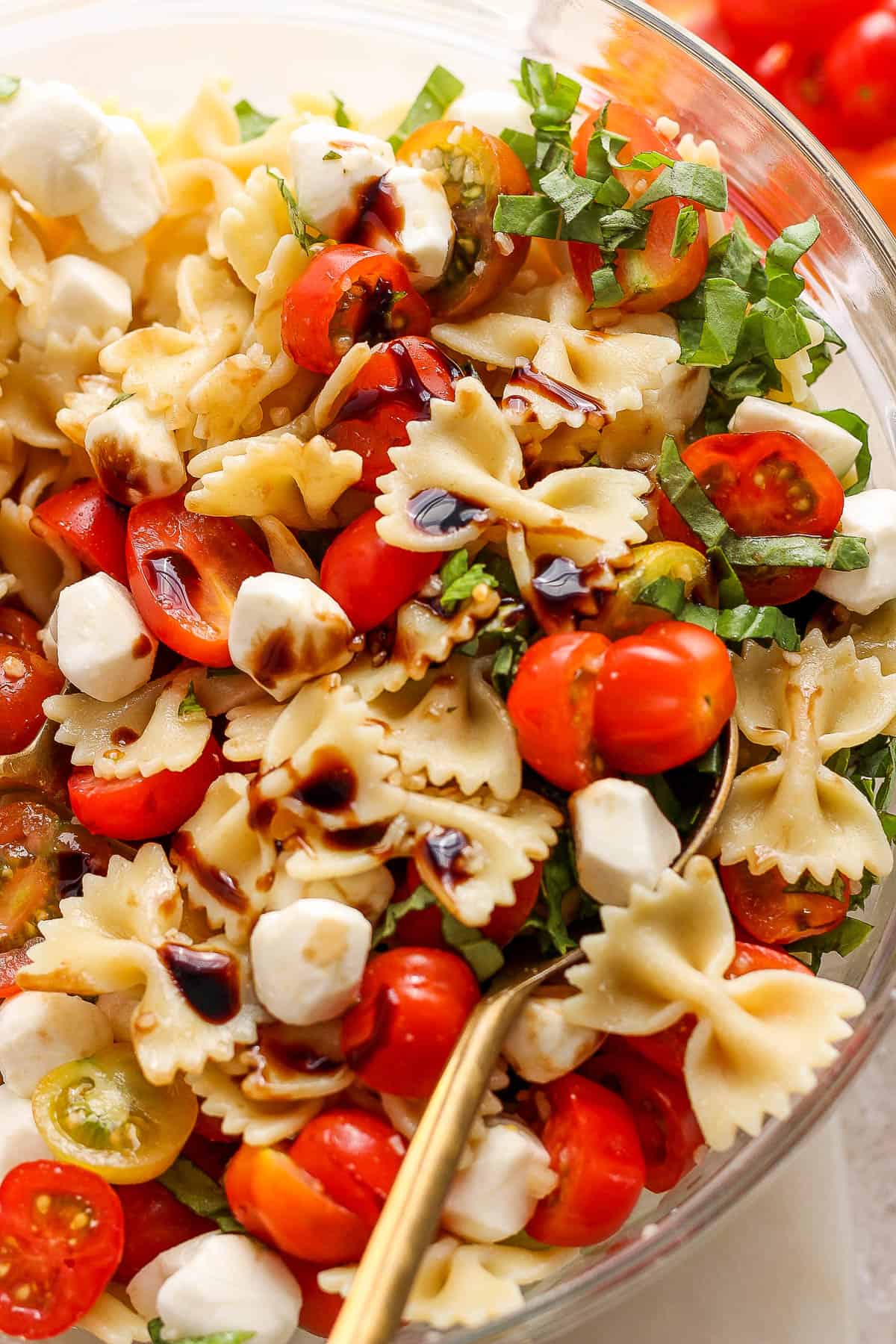 A caprese pasta salad drizzled with balsamic glaze.