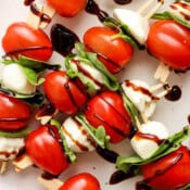 Top down shot of caprese skewers with cherry tomatoes, mini mozzarella balls, fresh basil and balsamic glaze.