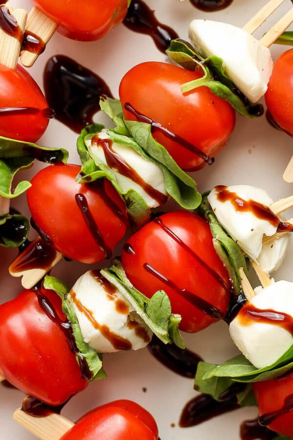 Top down shot of caprese skewers with cherry tomatoes, mini mozzarella balls, fresh basil and balsamic glaze.