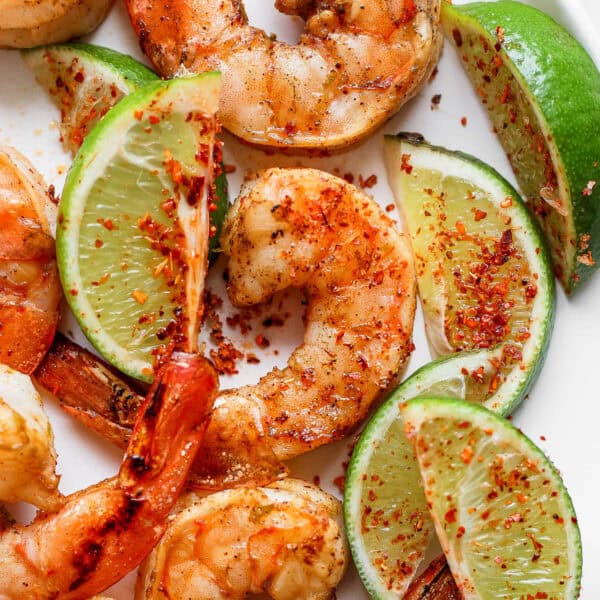 Top down shot of a plat of chili lime shrimp with slices of lime.