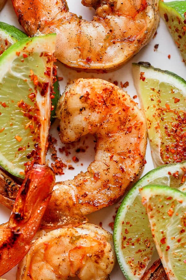 Top down shot of a plat of chili lime shrimp with slices of lime.