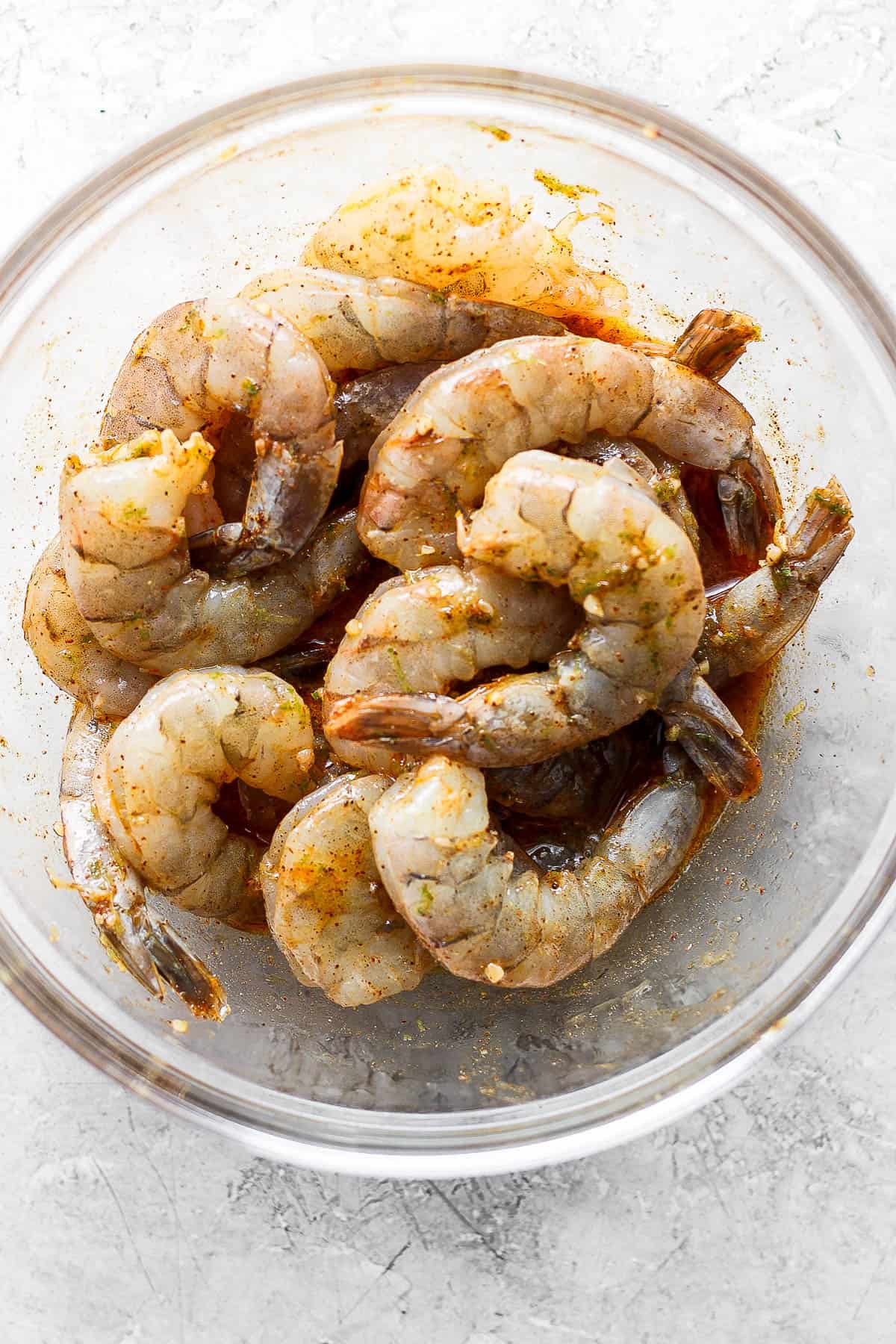 Shrimp marinating in a large glass bowl.
