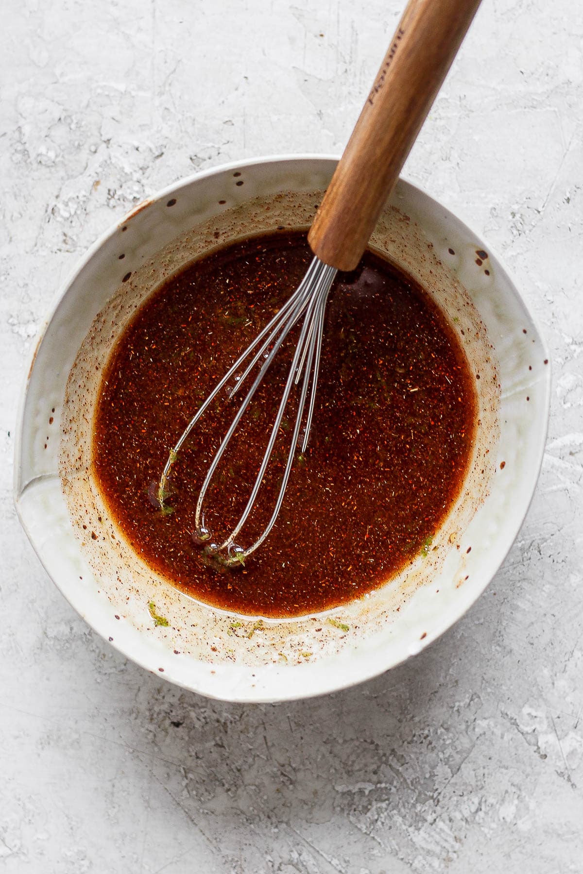 Chili lime shrimp marinade in a bowl with a whisk.