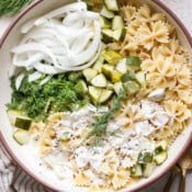 Top down shot of a big bowl of dill pickle pasta salad with white onions, dill and chopped pickles.
