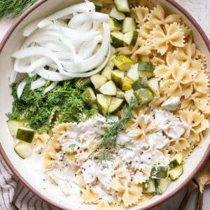 Top down shot of a big bowl of dill pickle pasta salad with white onions, dill and chopped pickles.