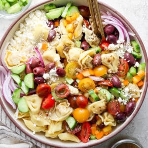 Top down up close shot of a big bowl of Greek Tortellini Pasta Salad with tortellini, feta, tomato, red onion and cucumber.