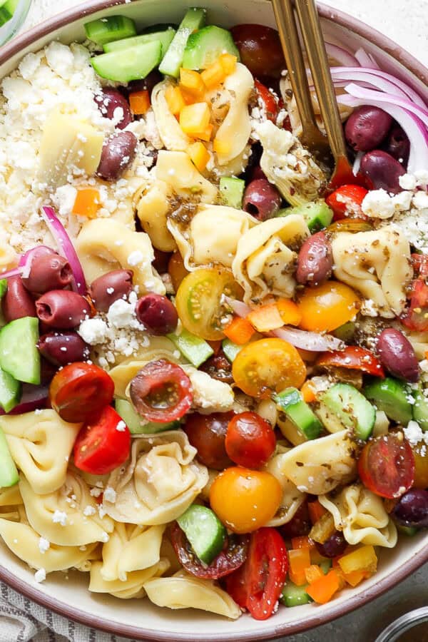 Top down up close shot of a big bowl of Greek Tortellini Pasta Salad with tortellini, feta, tomato, red onion and cucumber.