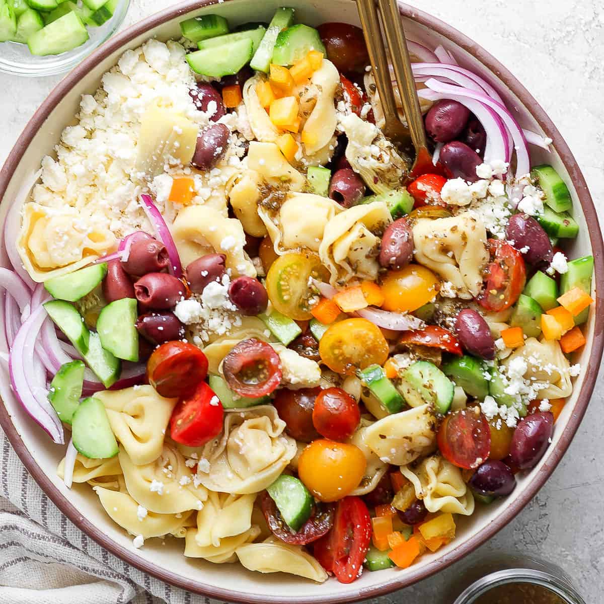 Top down up close shot of a big bowl of Greek Tortellini Pasta Salad with tortellini, feta, tomato, red onion and cucumber.