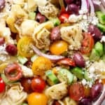 Top down up close shot of a big bowl of Greek Tortellini Pasta Salad with tortellini, feta, tomato, red onion and cucumber.