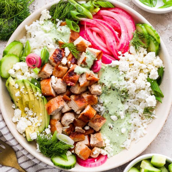 Top down shot of a Green Goddess Bowl with grilled chicken, avocado, pickled onions, dressing and feta.