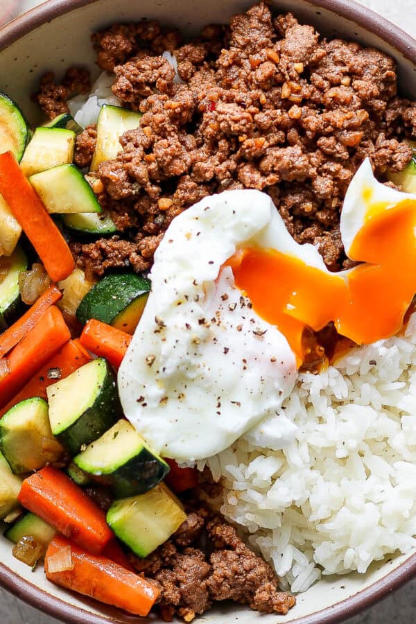Top down shot of a Ground Beef Rice Bowl with veggies and poached egg on top.
