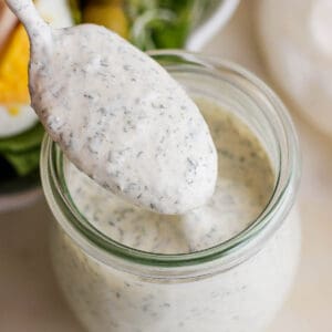 A small jar of homemade ranch dressing with a spoon lifting some out.