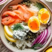 Top down shot of a Lox Bagel Rice Bowl with soft boiled egg, lox, rice, capers and lemon.