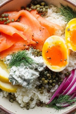 Top down shot of a Lox Bagel Rice Bowl with soft boiled egg, lox, rice, capers and lemon.