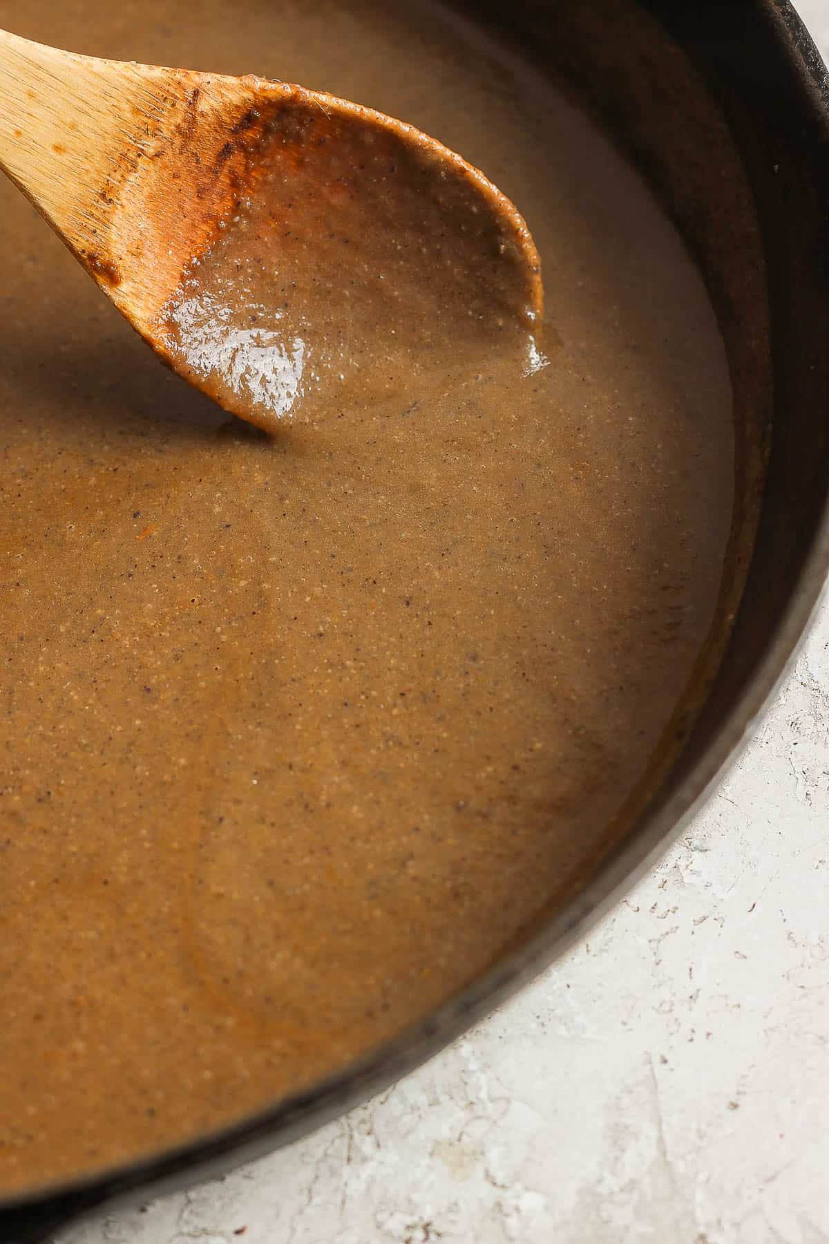 Mole sauce in the pan with a wooden spoon.
