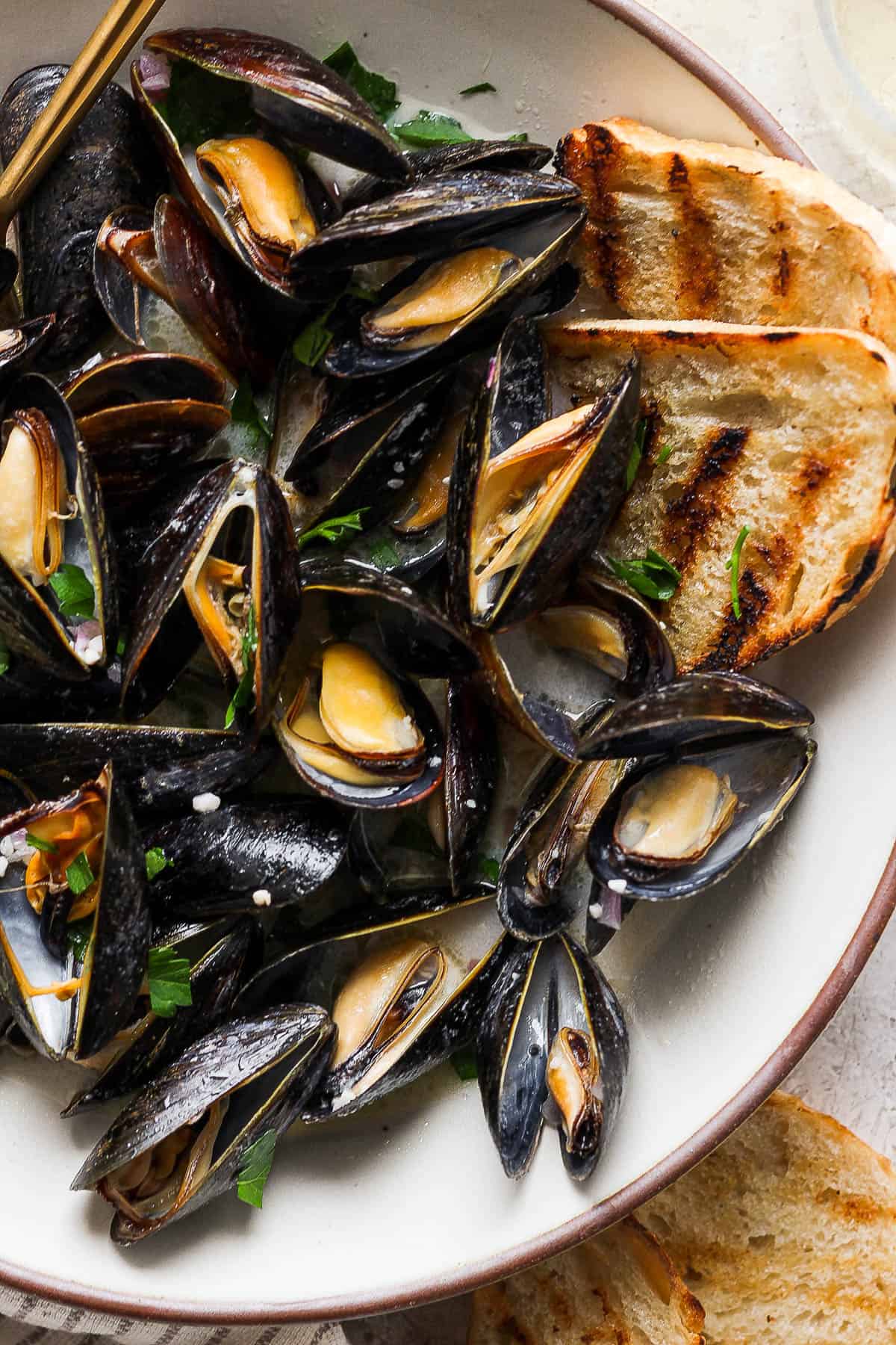 Bowl of mussels with grilled bread.