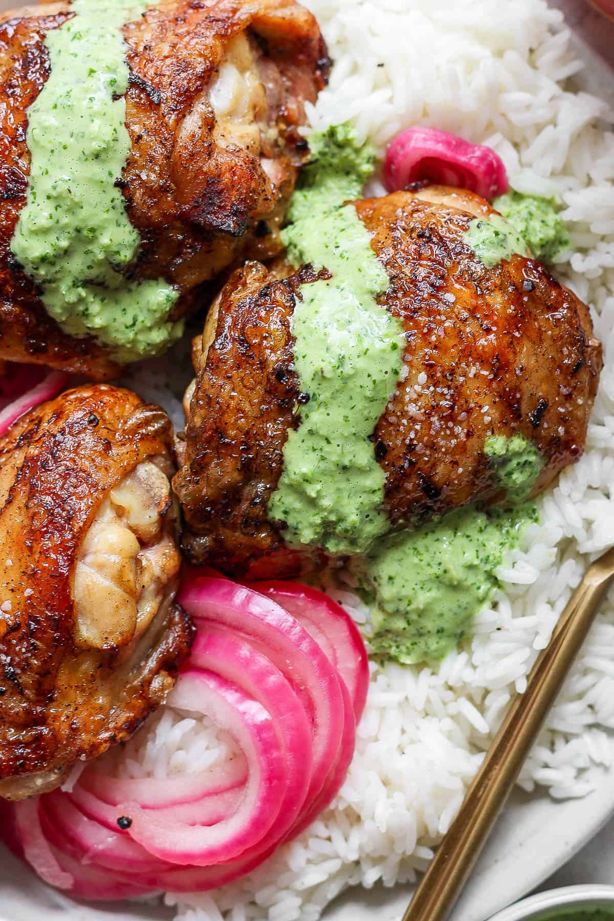 Peruvian chicken over rice with green sauce over a bed of rice.