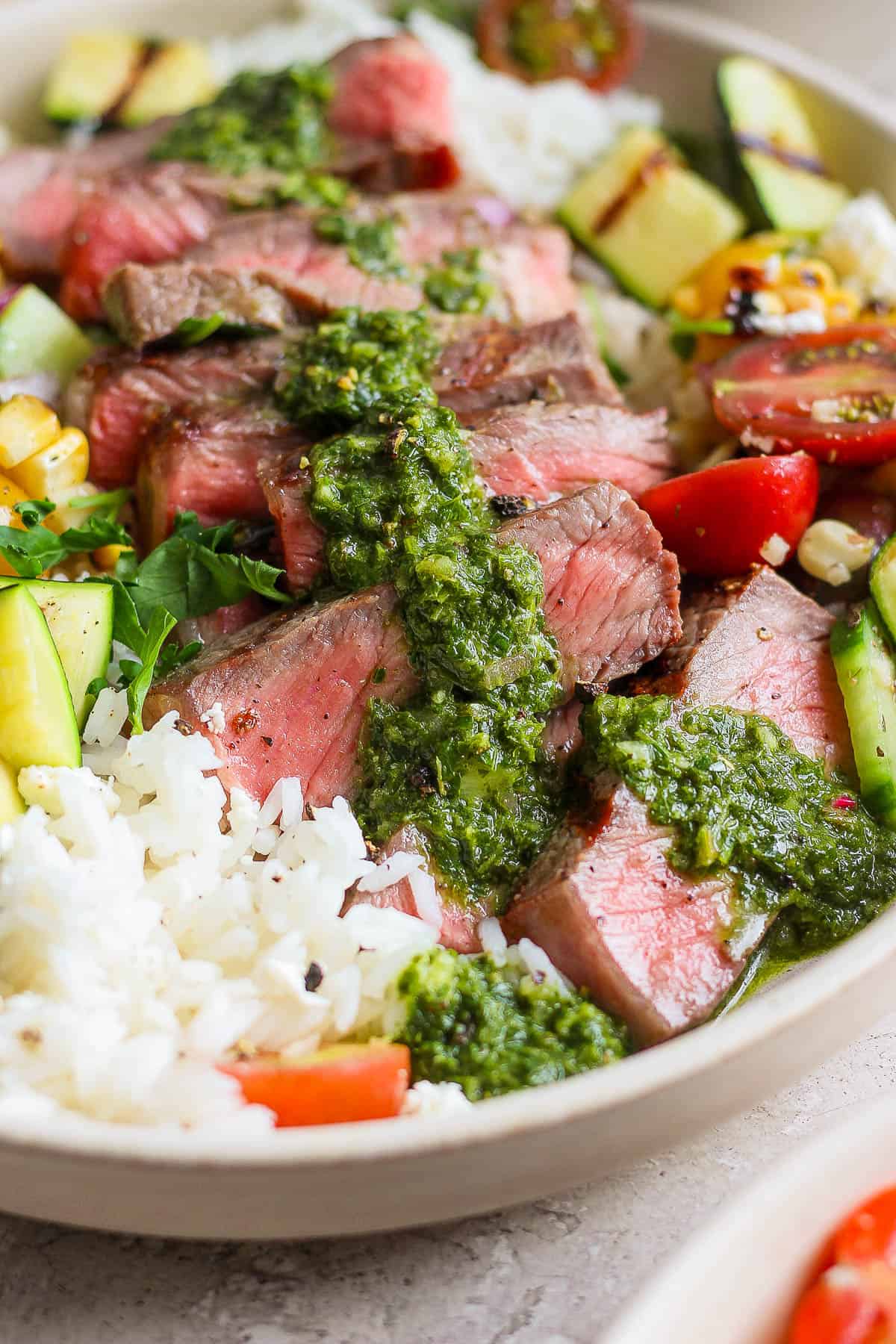 Close up of chimichurri on top of sliced steak in the steak rice bowl.