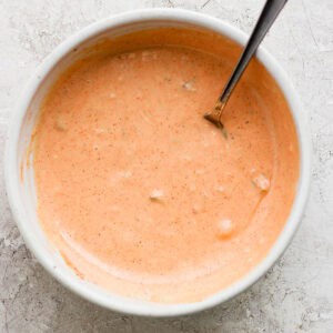 Top down shot of bowl of big mac sauce with a spoon sticking out.