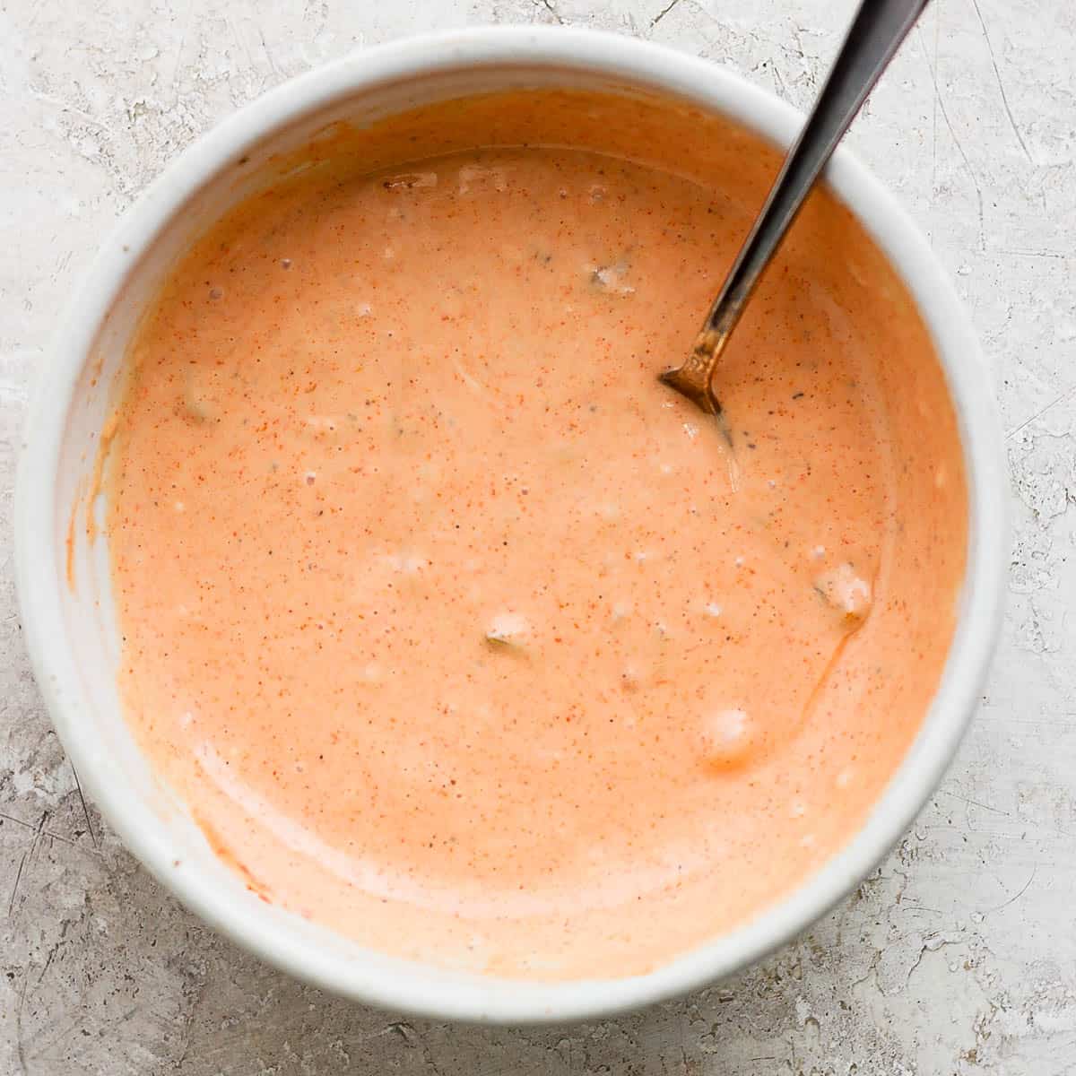 Top down shot of bowl of big mac sauce with a spoon sticking out.