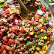 Top down shot of a big bowl of homemade cowboy caviar with two gold spoons sticking out.