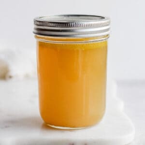 Homemade chicken broth in a mason jar with a lid on top.
