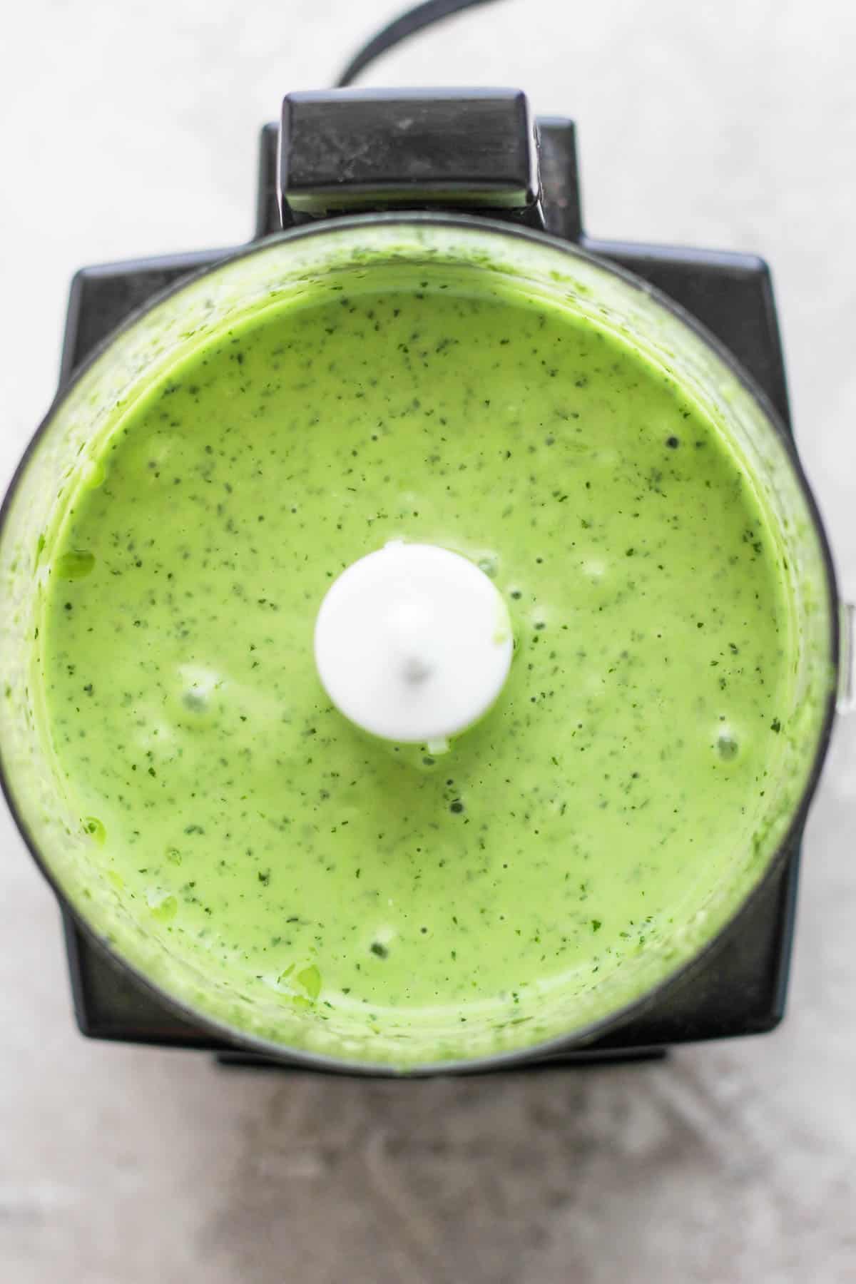 The creamy basil sauce in a food processor.