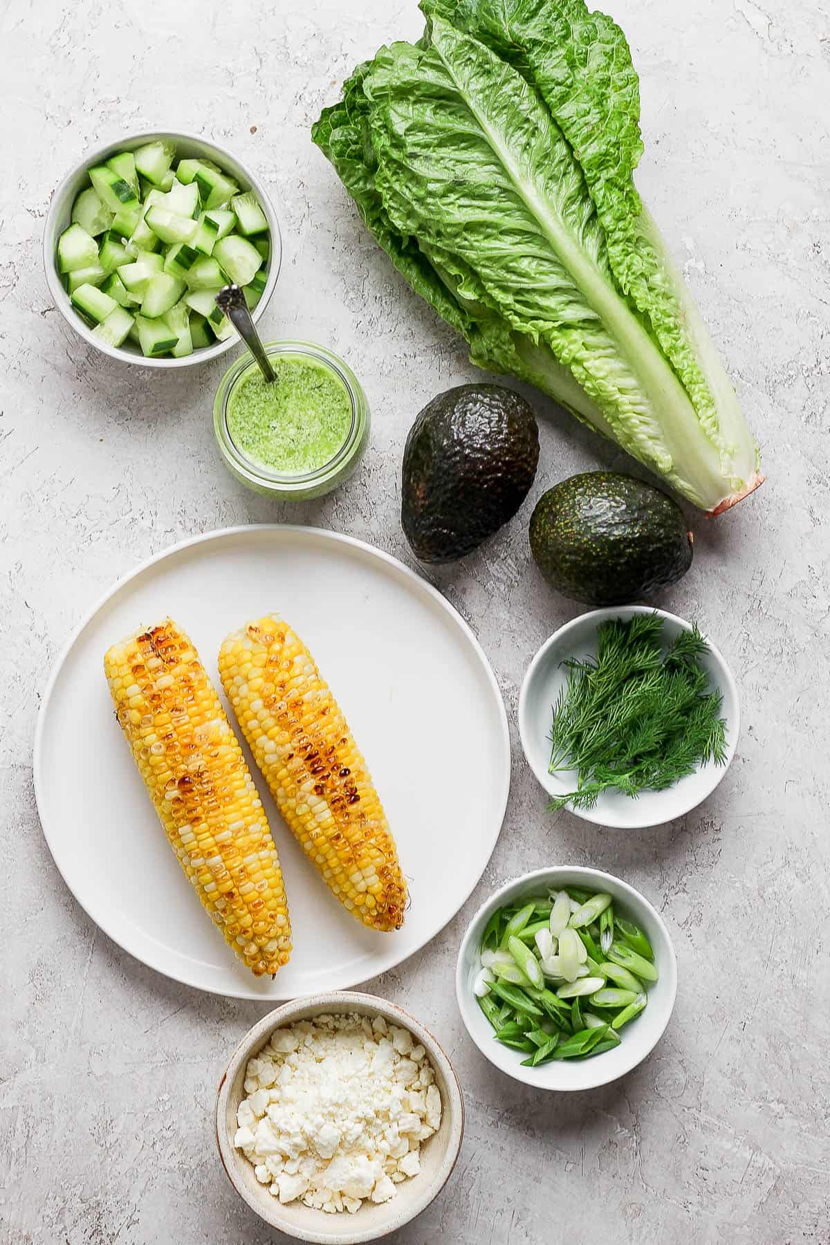 Ingredients for an avocado salad on the counter and in bowls.