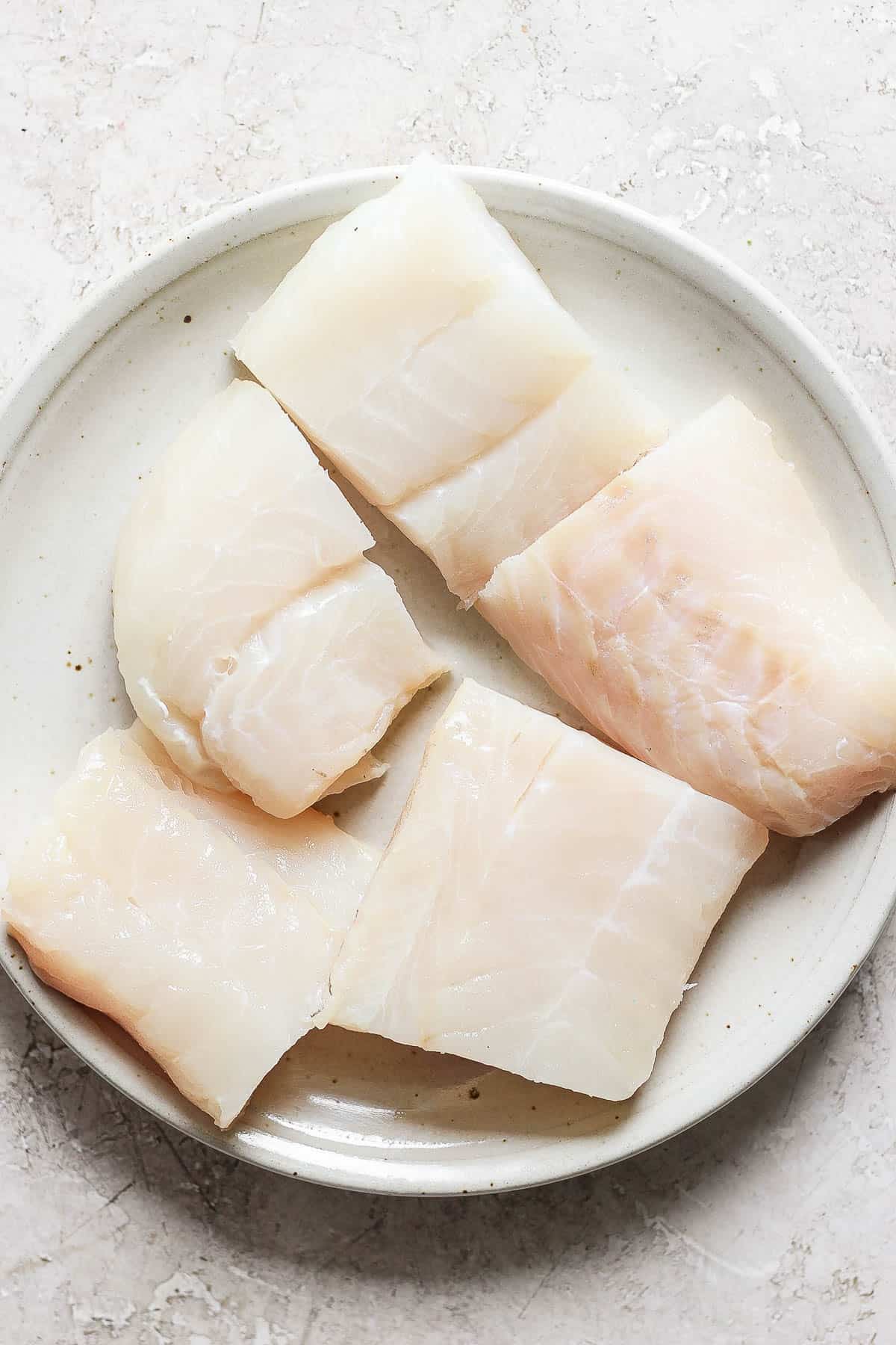 Large chunks of cod fillets on a large plate.
