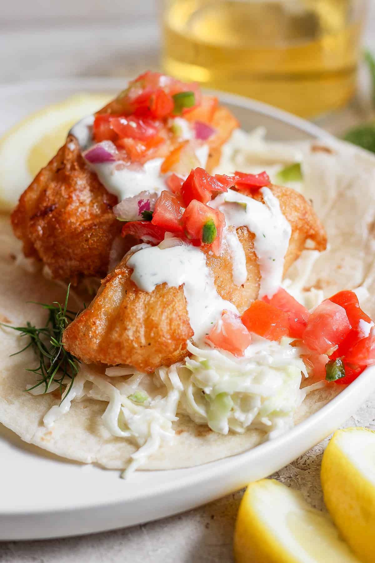 A fully assembled fish taco on a plate.