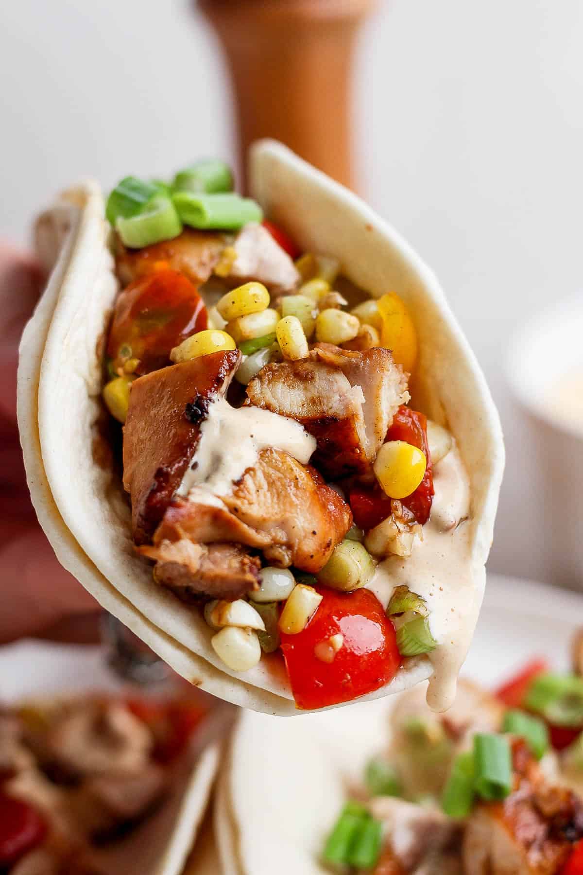 A hand holding the chicken taco with all the toppings.