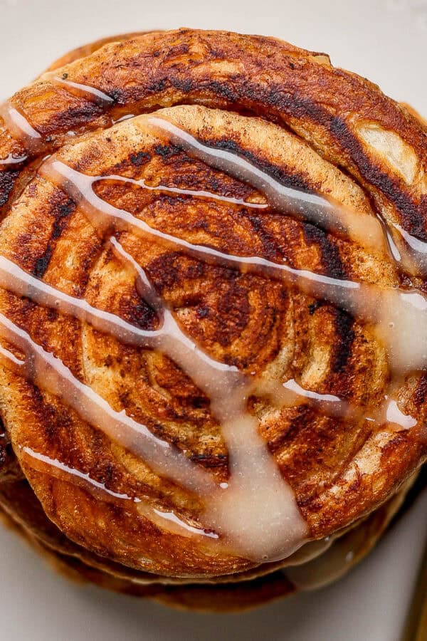 Top down shot of a stack of smashed cinnamon rolls with frosting drizzled over top.
