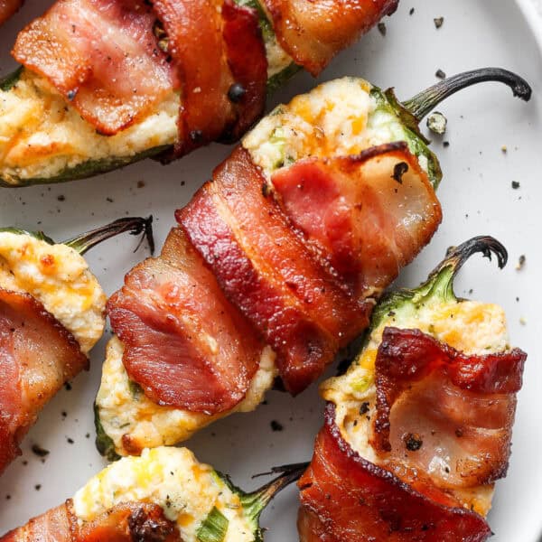 Top down shot and a close up of a bacon-wrapped grilled jalapeno popper on a plate.