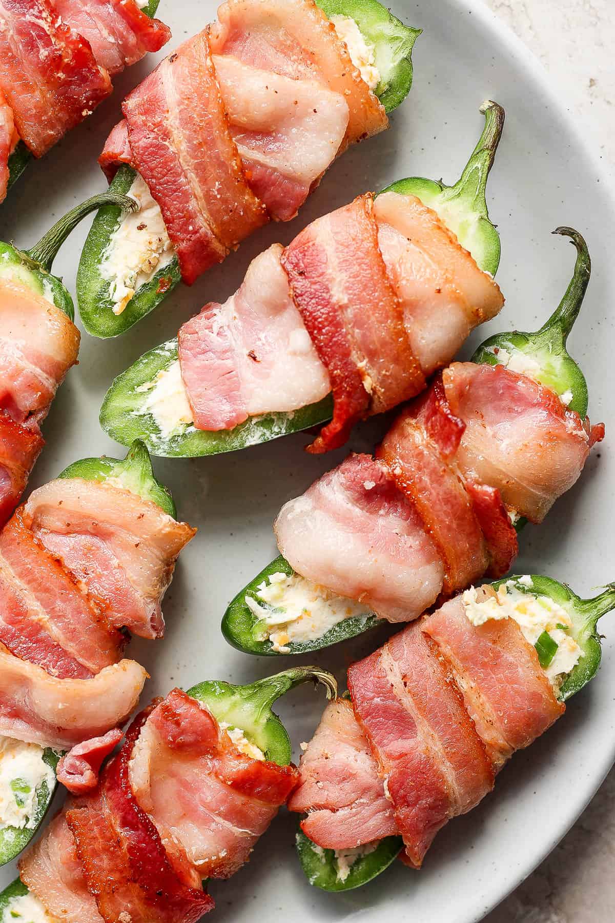 Pepper halves filled with the cheese filling and wrapped in bacon before grilling.