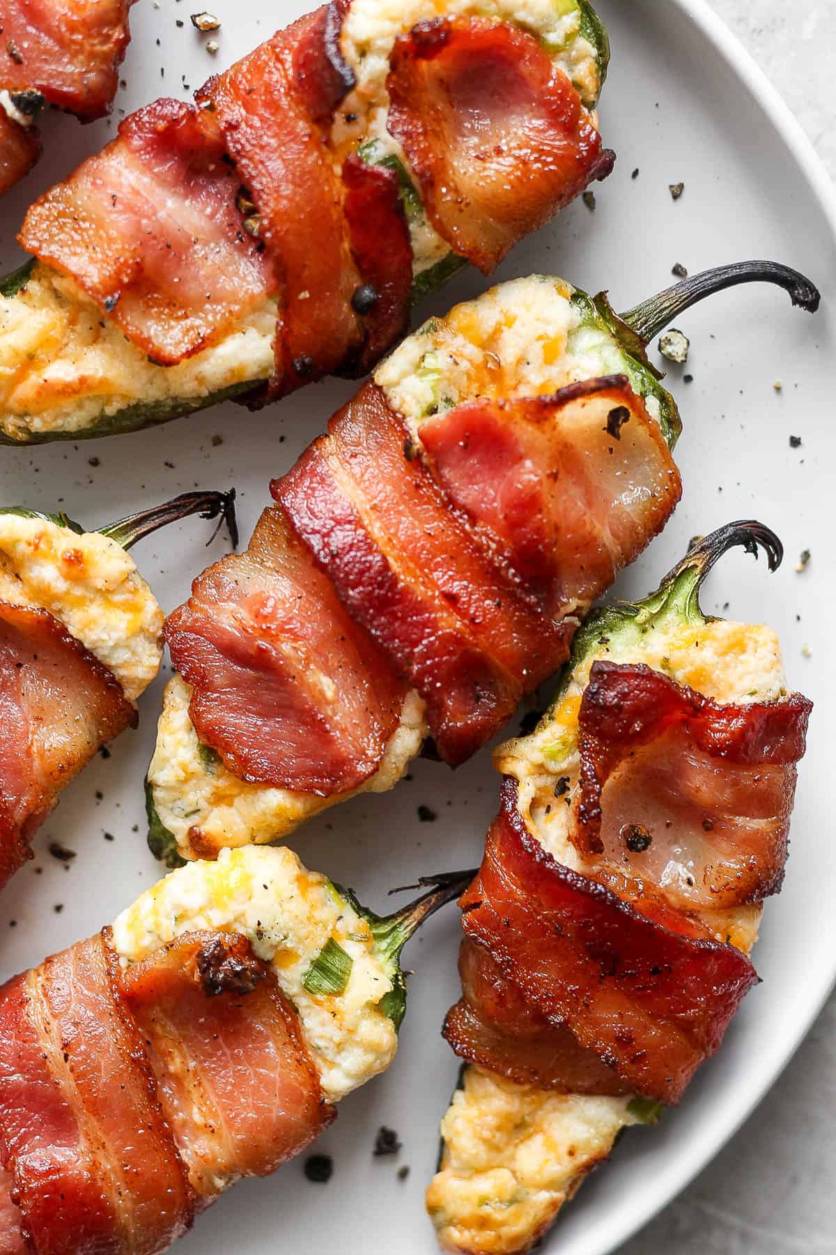 Fully cooked jalapeño poppers on a white plate.