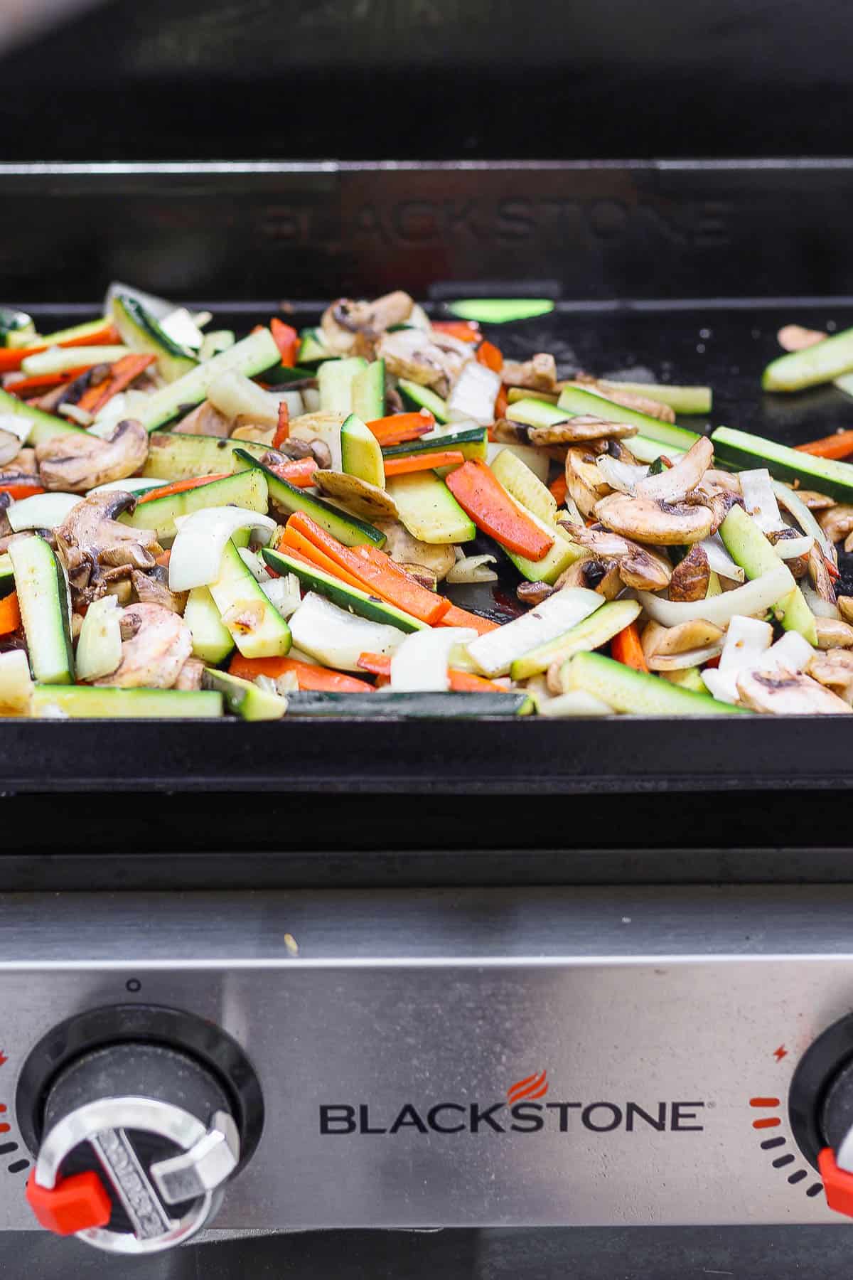 The hibachi vegetables cooking on the hot griddle.