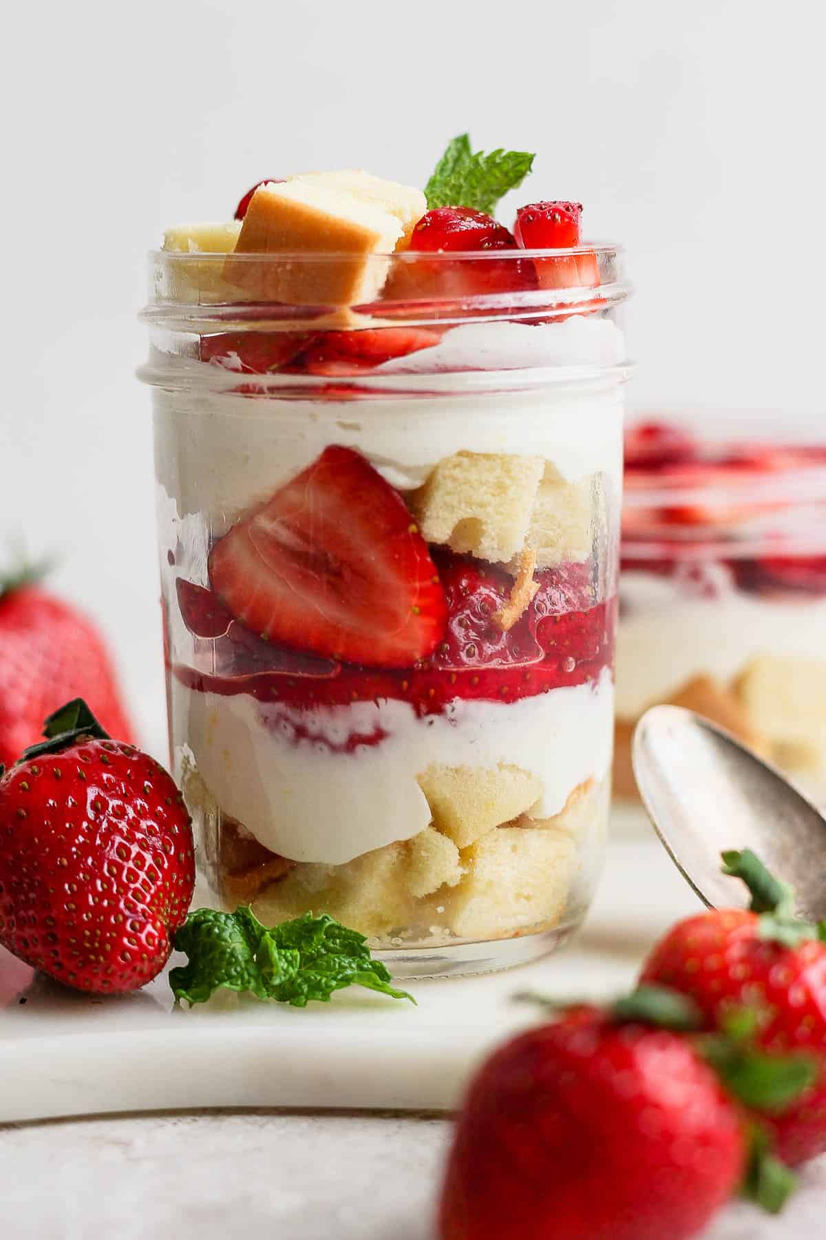 A layered strawberry shortcake parfait in a mason jar.