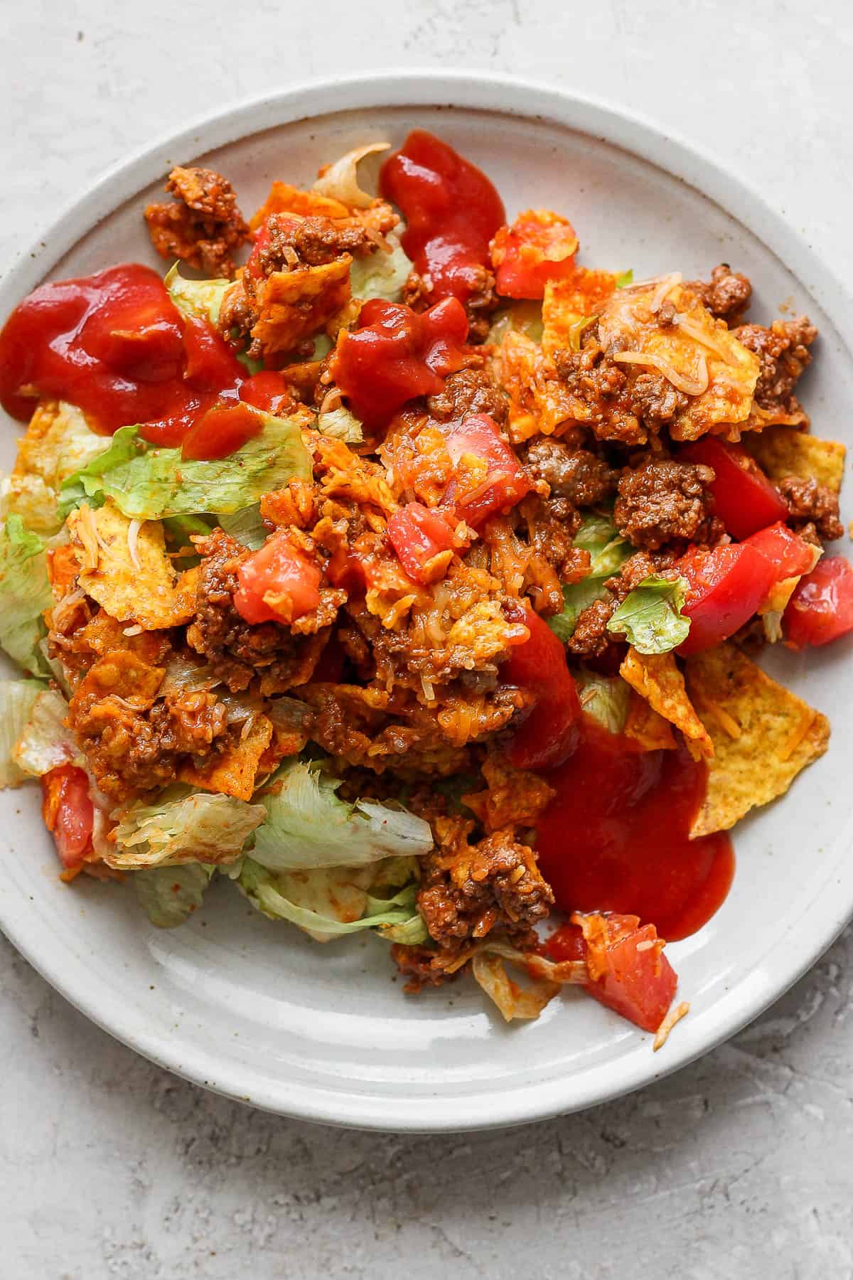 Taco salad on a plate with some dressing on top.