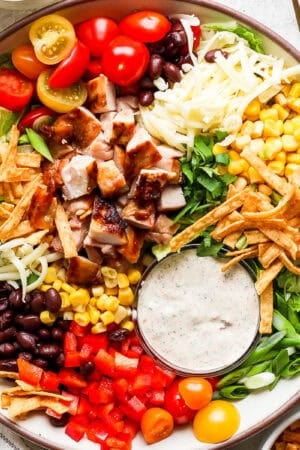 A big bowl of chopped Tex Mex Salad with tomatoes, black beans, cheese, corn, tortilla strips, grilled chicken and chipotle ranch dressing.
