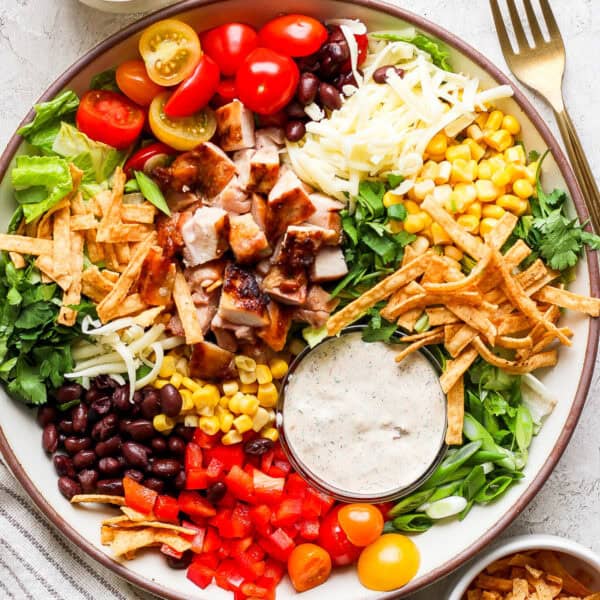 A big bowl of chopped Tex Mex Salad with tomatoes, black beans, cheese, corn, tortilla strips, grilled chicken and chipotle ranch dressing.