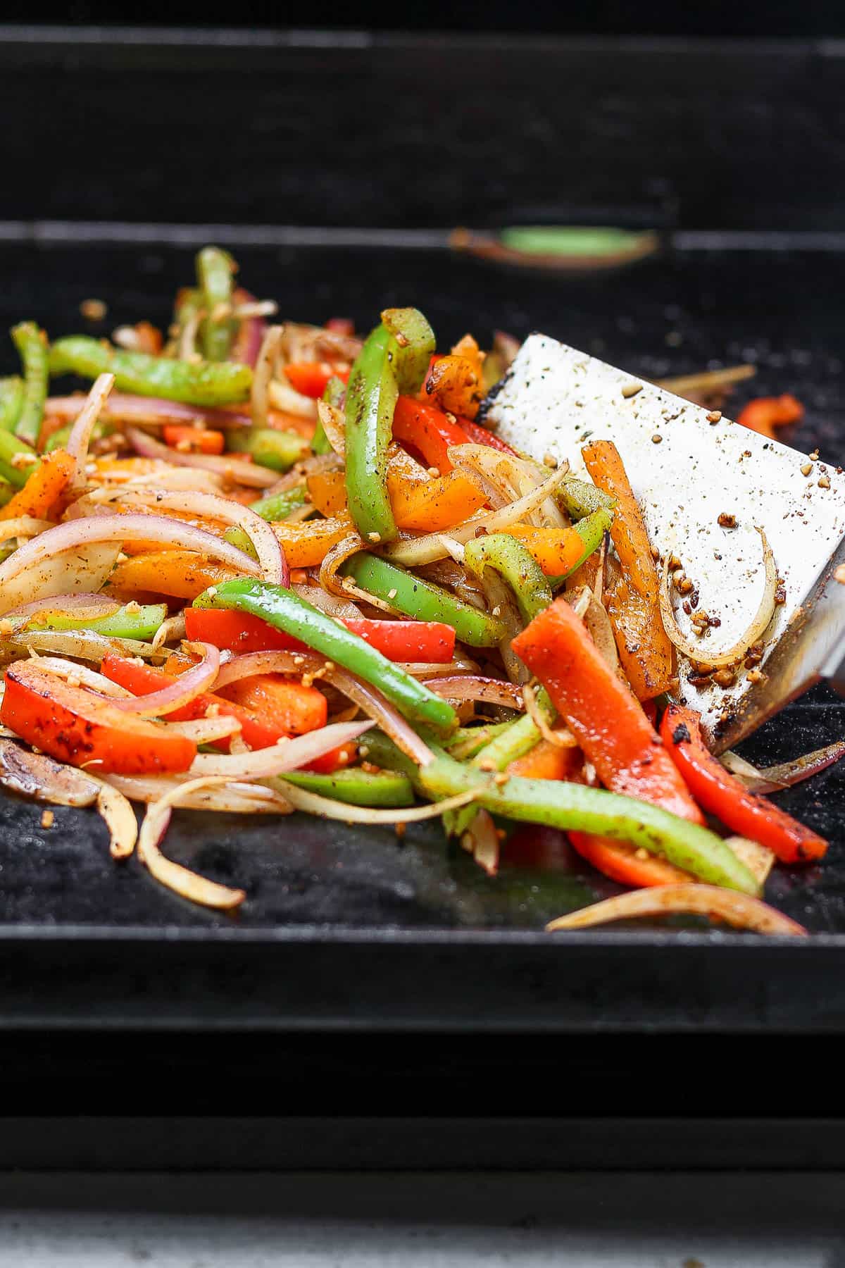 A large spatula moving the fajita veggies around the cooking surface.